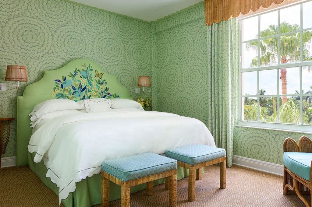 room with green wallpaper bed and stools