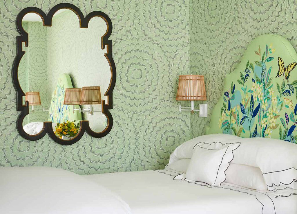 bed with green floral headboard and mirror on wall