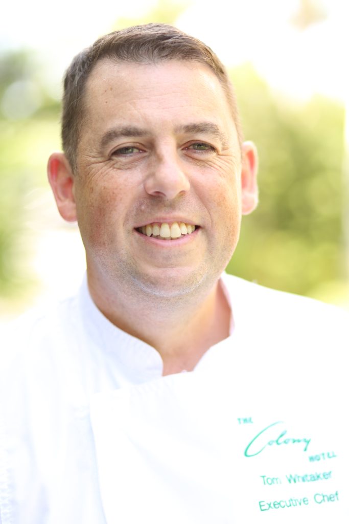 Male chef in a white chef jacket smiling