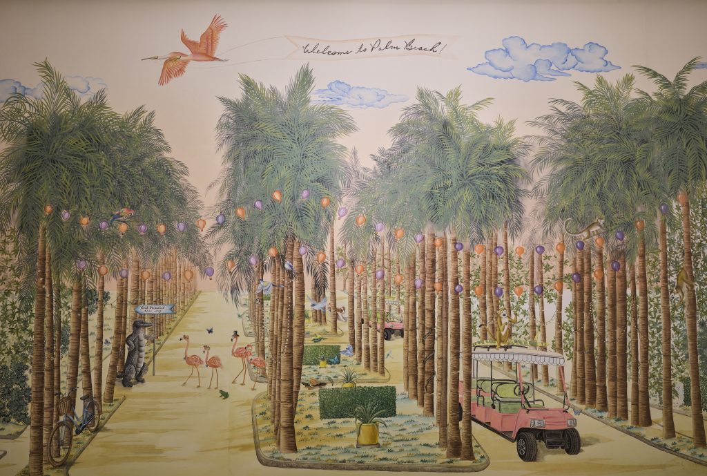 The Colony Hotel Hallway with palm trees, bech buggy, string lights, flamingos, an alligator and a welcome to Palm Beach banner flown by a bird