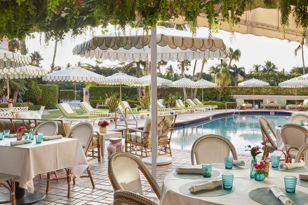 Swifty's poolside restaurant, pool, umbrellas, dining tables set with flatware and glasses, placemats