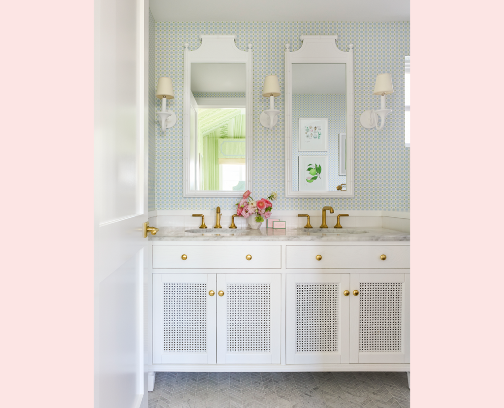Bathroom with double vanity sinks, white vanities, two whit rectangular mirrors on the wall, gold faucets, small wall mounted lamps on each side of the mirrors.
